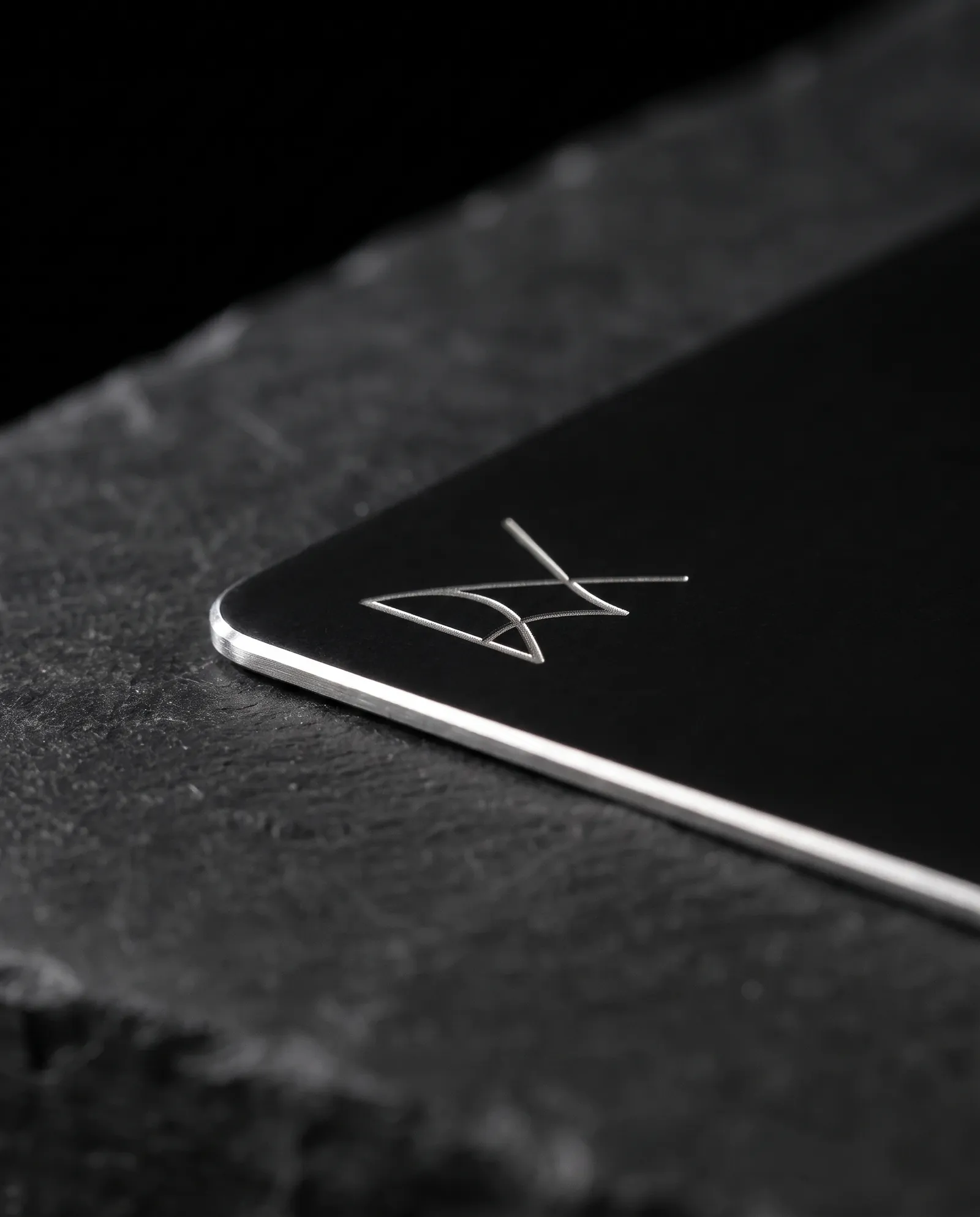Macro of a matte black metal card corner showing the bare steel edge and an engraved line