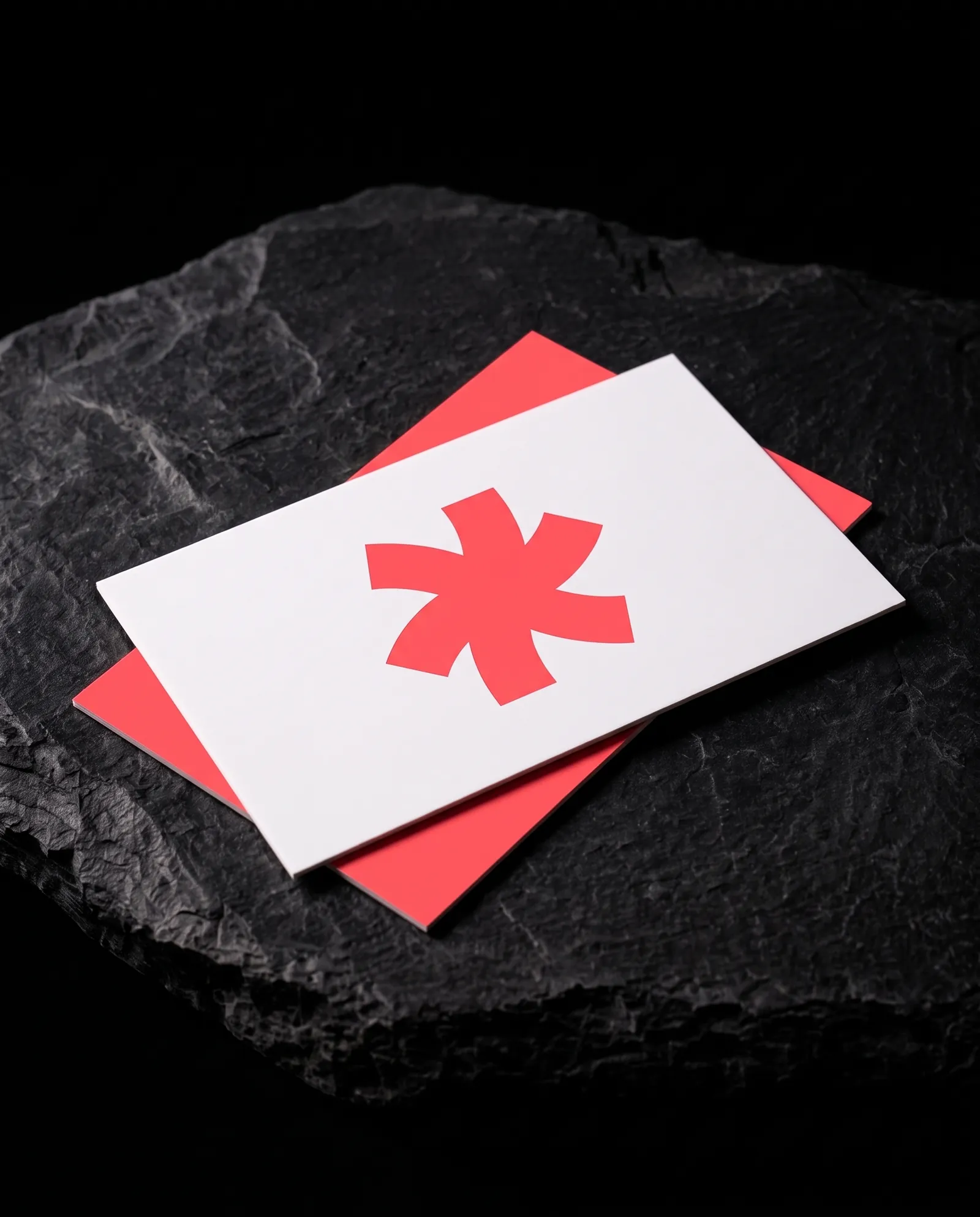 White 16pt matte business card with a coral Print Peppermint mark and no glare, over a coral card on black slate