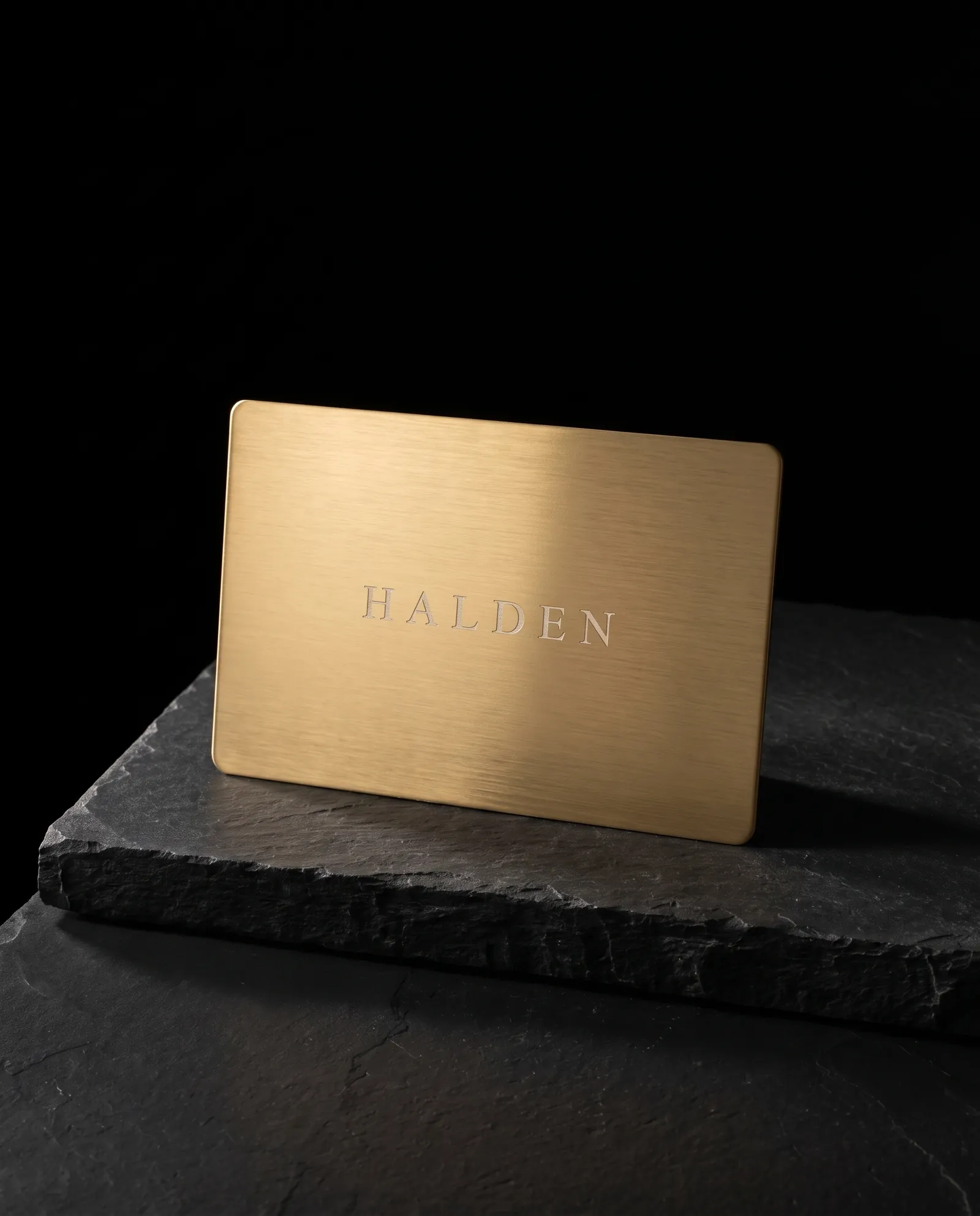 Brushed gold stainless steel business card with engraved wordmark revealing silver steel