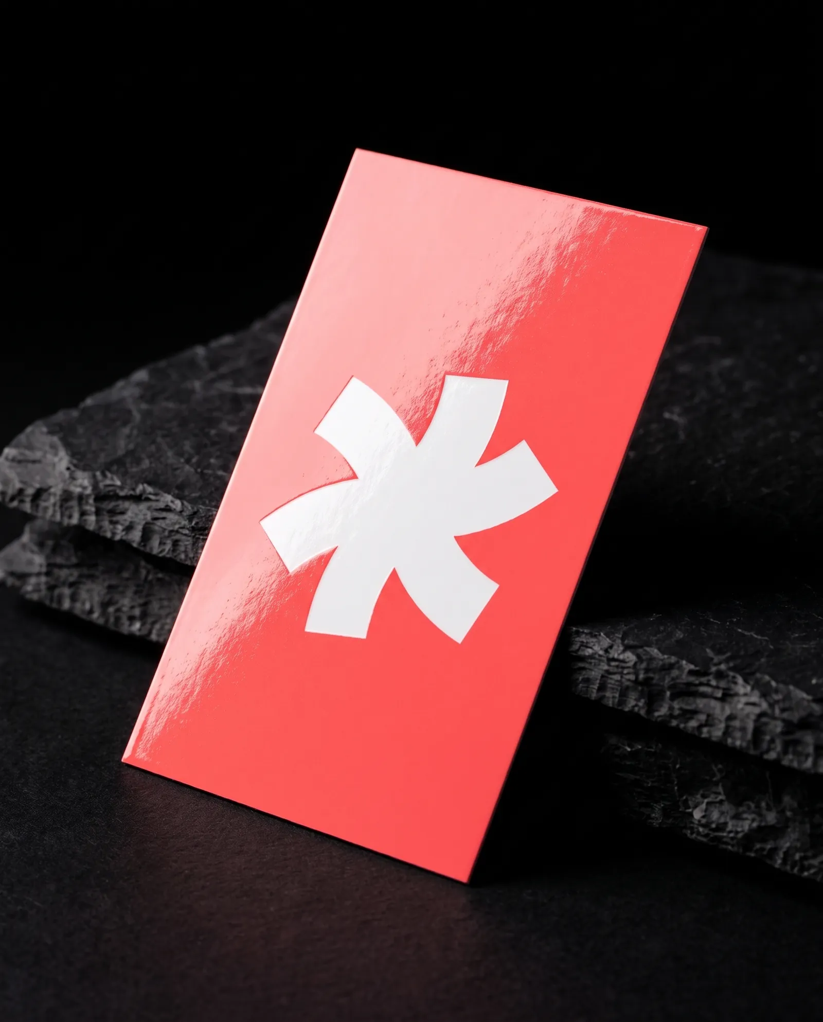 Full-bleed coral high-gloss business card with a white Print Peppermint mark, a bright highlight across the gloss coat